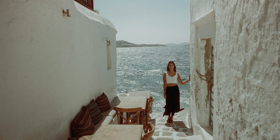 A girl in a flowy skirt and top standing near water