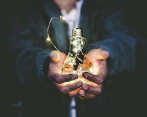 A man holding a lightbulb full of string lights.